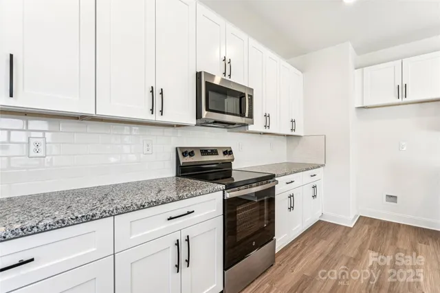 a kitchen with granite countertop a sink dishwasher a stove and a microwave oven with cabinets