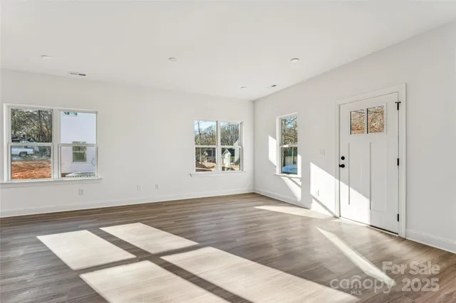a view of an empty room with window and wooden floor