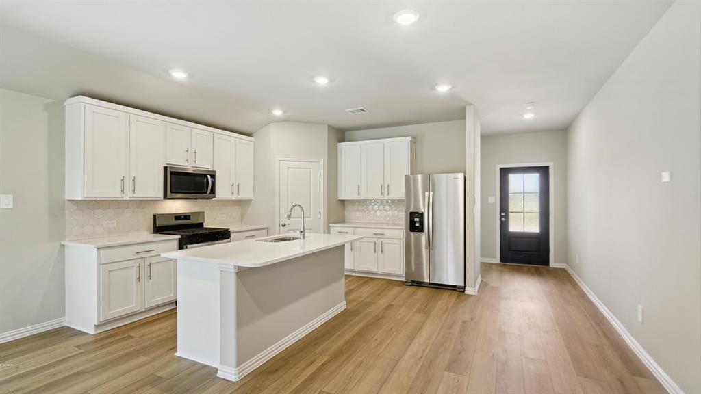 2215 Currents Road Princeton, TX 75407 - Photo 11 of 37 a kitchen with stainless steel appliances a stove top oven a refrigerator a sink and dishwasher with wooden floor