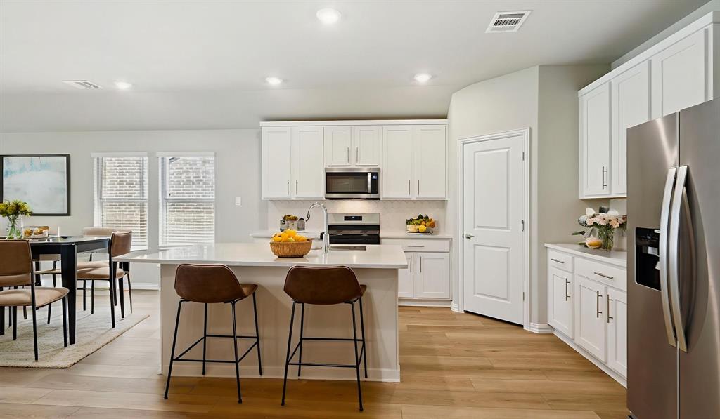 2215 Currents Road Princeton, TX 75407 - Photo 16 of 37 a kitchen with stainless steel appliances a refrigerator a stove a dining table and chairs