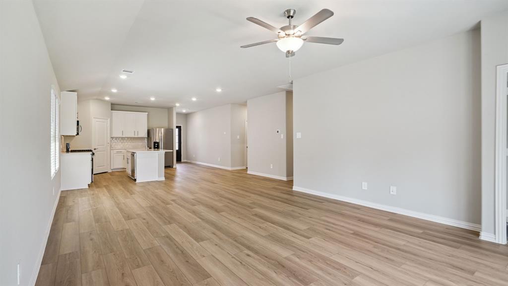 2215 Currents Road Princeton, TX 75407 - Photo 6 of 37 a view of an empty room with wooden floor and a kitchen