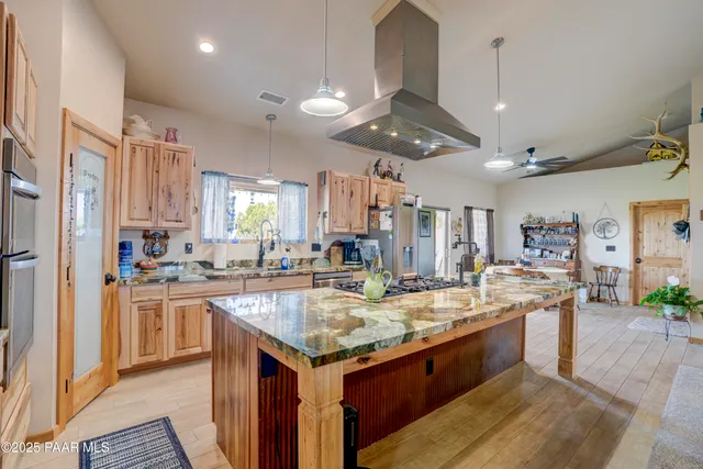 a large kitchen with kitchen island a large counter space a sink appliances and cabinets