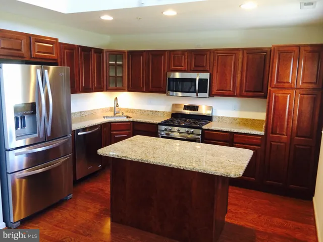 a kitchen with stainless steel appliances wooden cabinets a stove a sink and a refrigerator