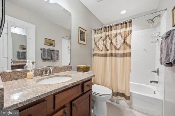 a bathroom with a granite countertop sink toilet a mirror a bathtub and shower