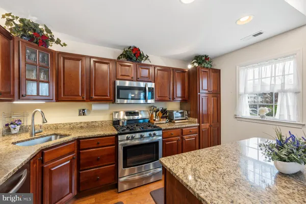 a kitchen with stainless steel appliances granite countertop a sink stove and cabinets
