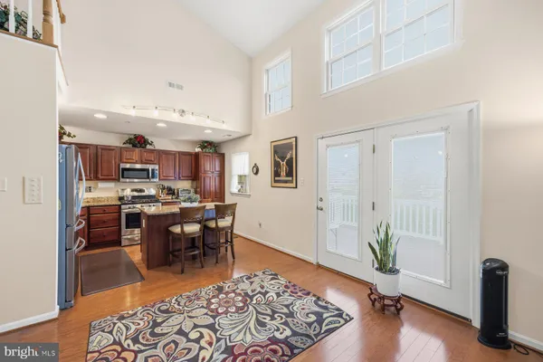 a living room with stainless steel appliances furniture rug and wooden floor