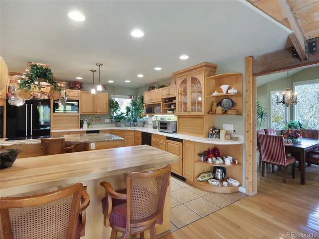 a room with stainless steel appliances lots of wooden furniture dining table and chairs