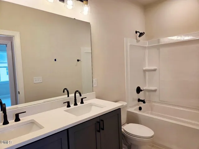 a bathroom with a bathtub shower sink vanity mirror and toilet