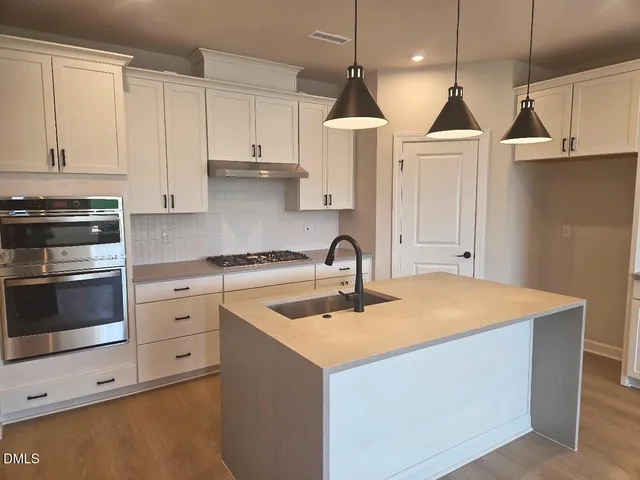 a kitchen with stainless steel appliances granite countertop a sink a stove and a refrigerator