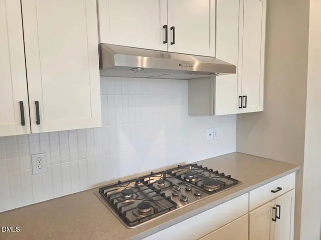a kitchen with white cabinets and a stove