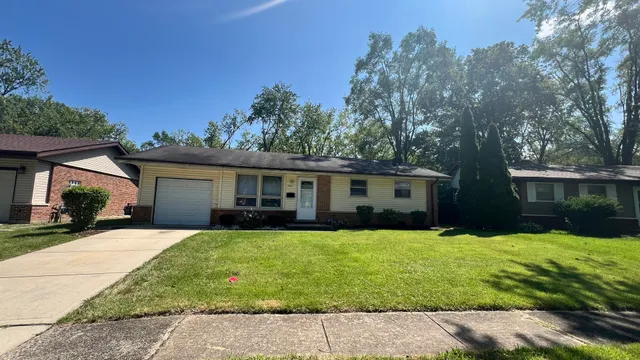 a front view of house with yard and trees in the background