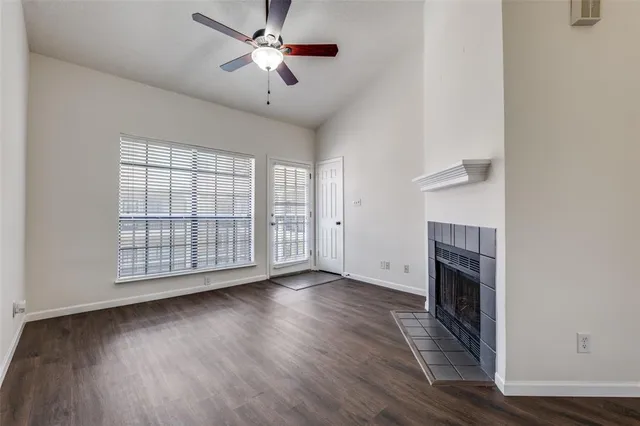 an empty room with windows fireplace and wooden floor