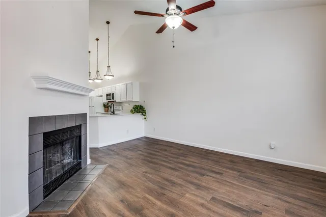 a view of an empty room with wooden floor and a fireplace