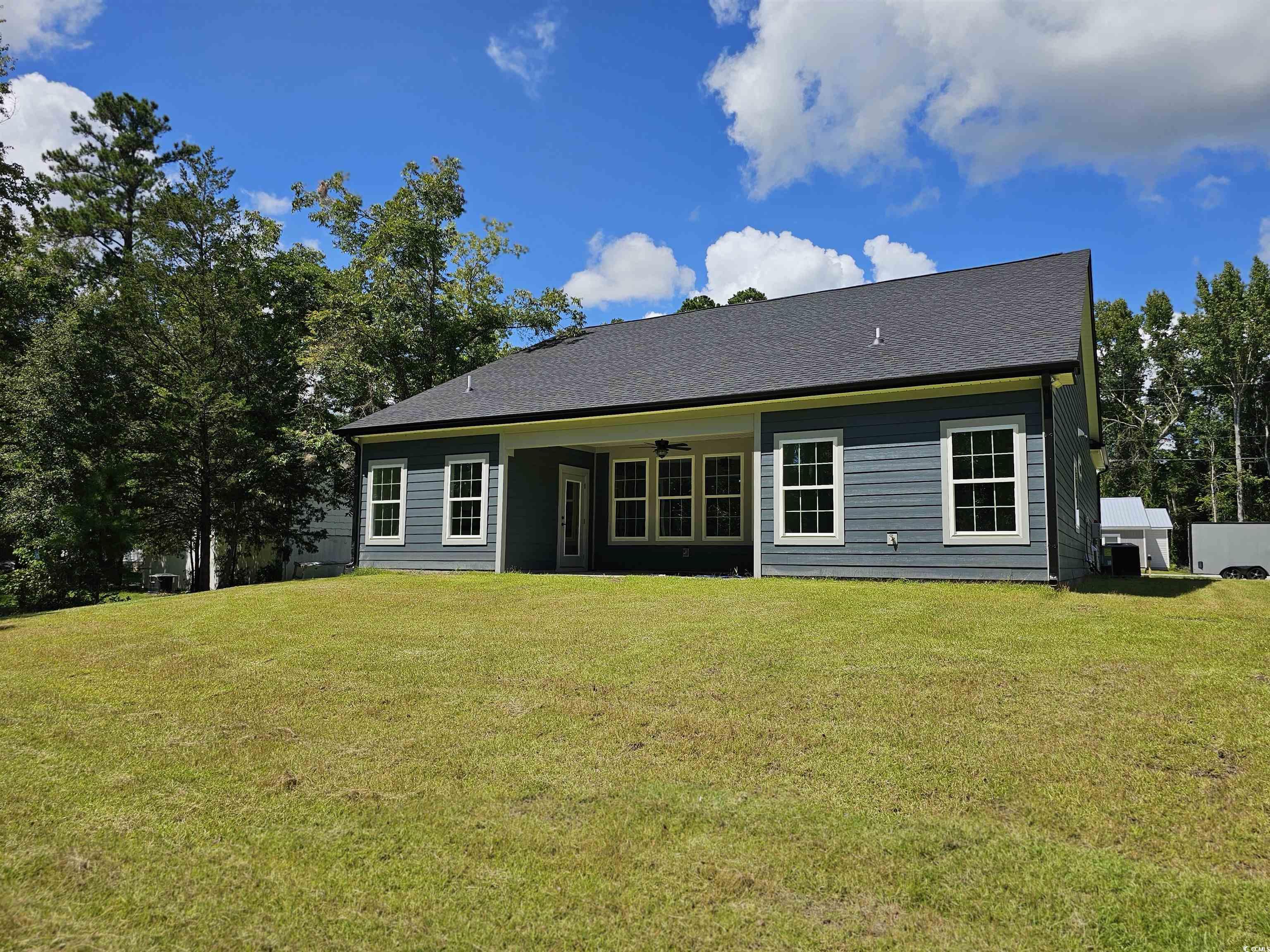 Rear view of property with ceiling fan and a yard