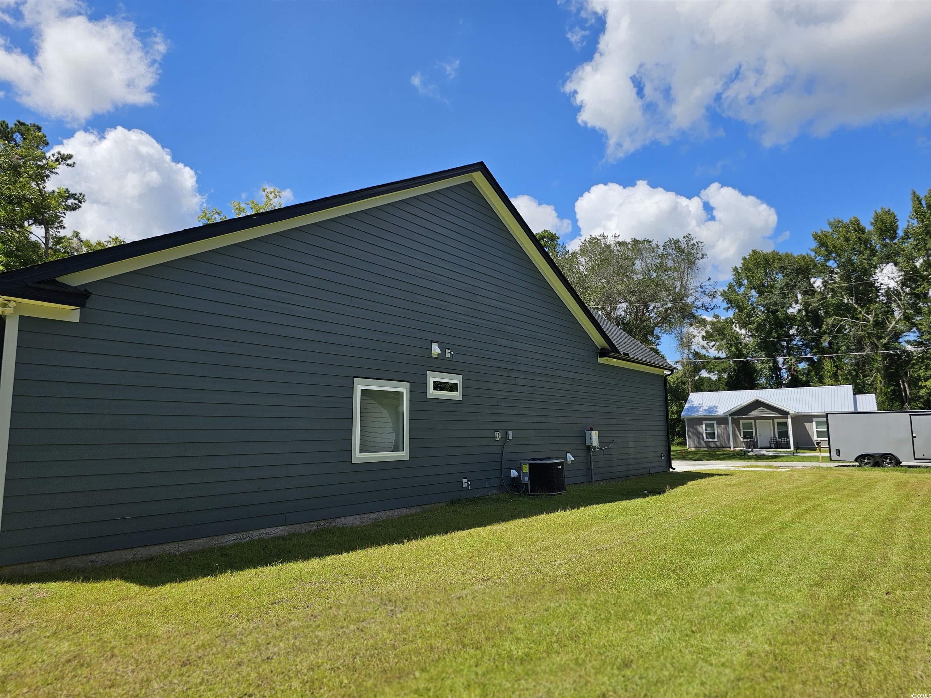 View of side of property featuring a lawn and cent