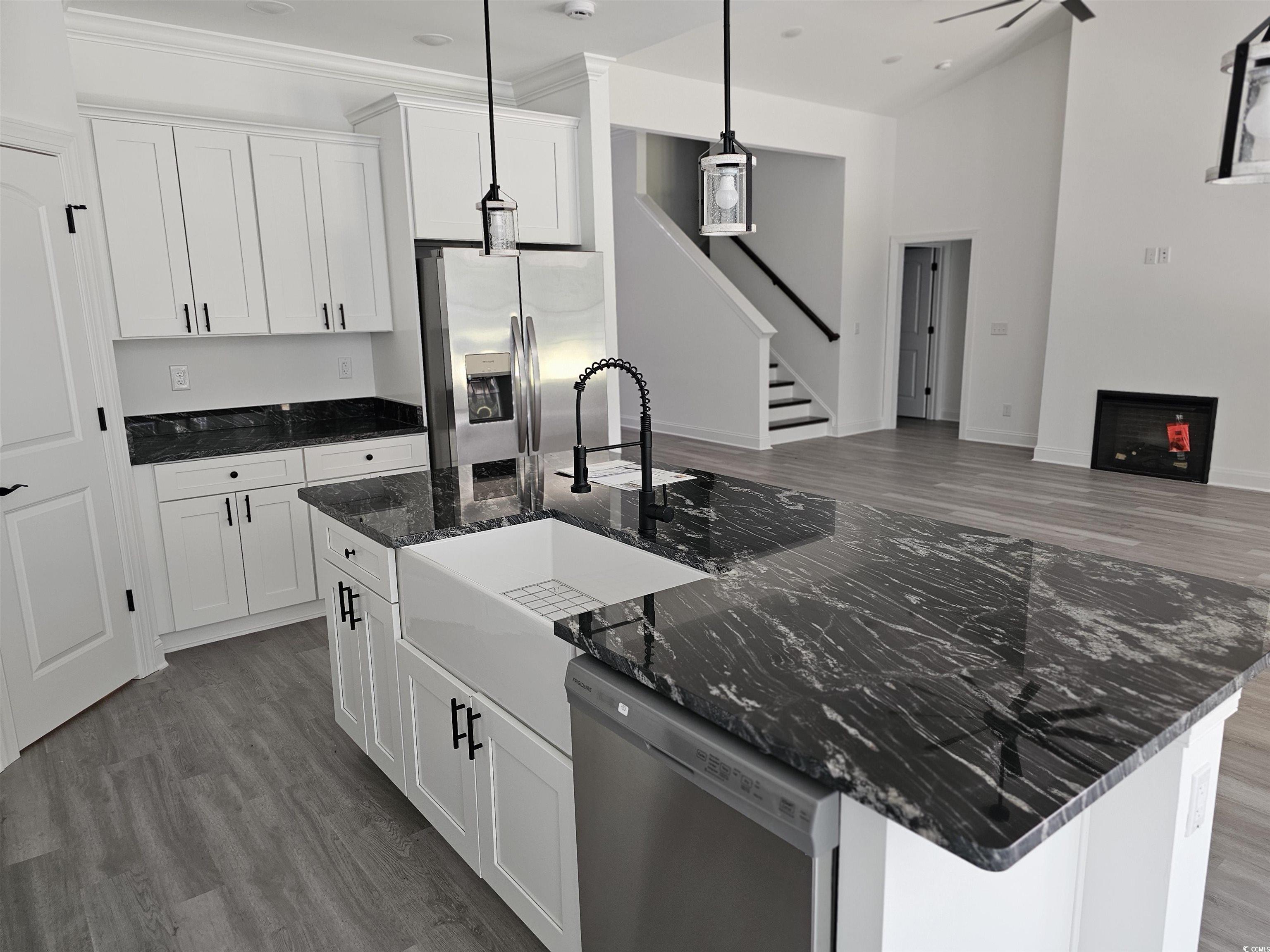 Kitchen with an island with sink, white cabinetry,