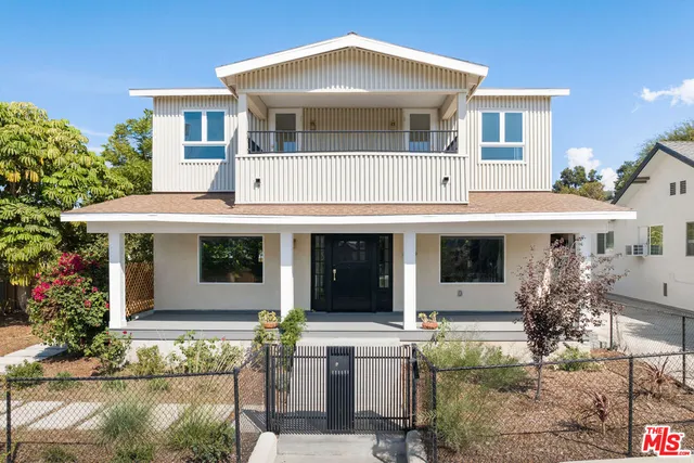 a view of a white house with large windows and a table and chairs in porch