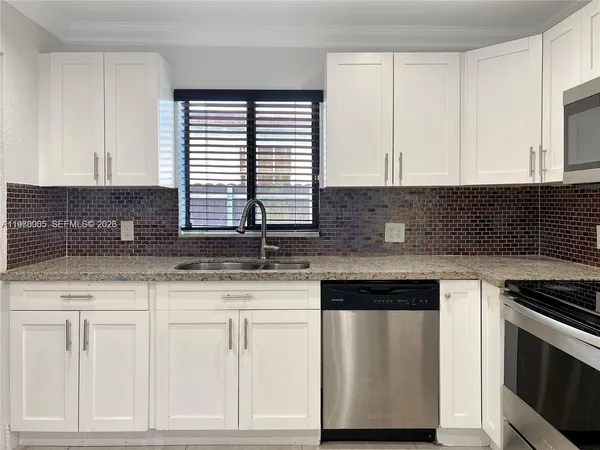 a kitchen with granite countertop white cabinets and white appliances