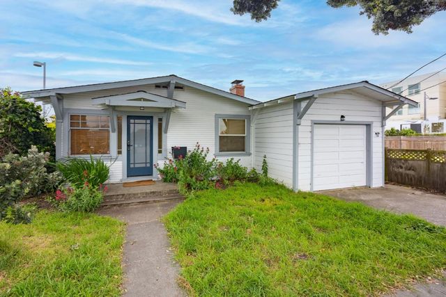 a view of a house with brick walls and a yard with plants