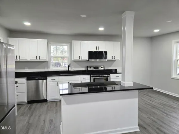 a kitchen with stainless steel appliances a sink a stove a microwave a center island and a window