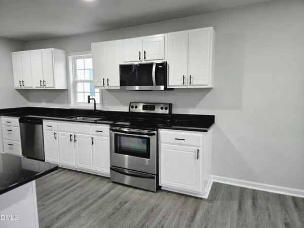 a white kitchen with granite countertop stainless steel appliances