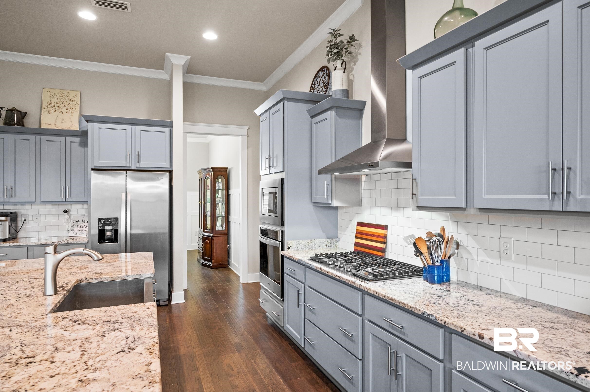 31355 Limpkin Street Daphne, AL 36527 - Photo 18 of 57 Kitchen featuring appliances with stainless steel finishes, ornamental molding, dark wood-type flooring, sink, and wall chimney range hood