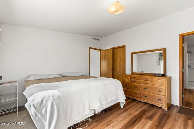 a bedroom with a bed and a flat tv screen on dresser