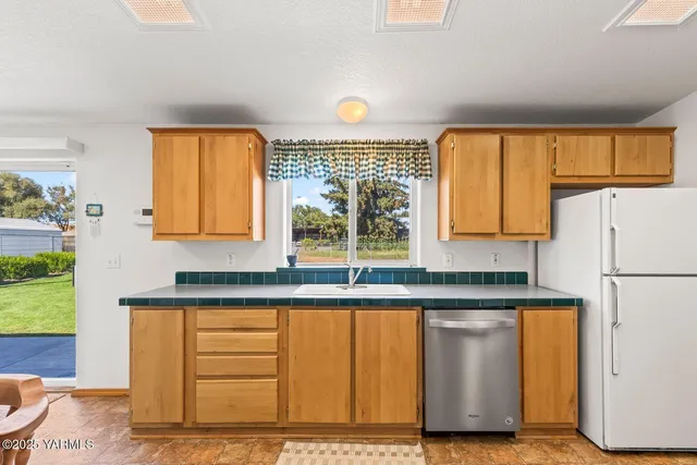 a kitchen with granite countertop a refrigerator a sink and a stove