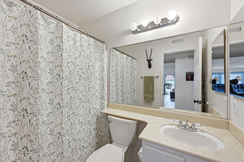 270 Chestnut Way Oceanside, CA 92057 - Photo 24 of 43 a bathroom with a sink a toilet a mirror and shower curtain
