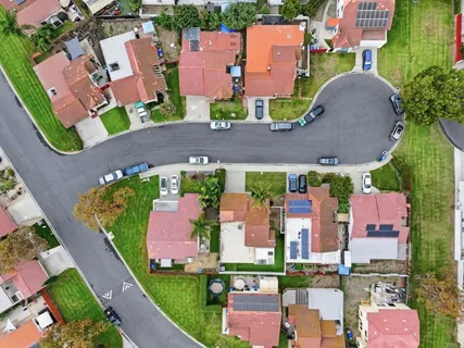 an aerial view of residential houses with outdoor space and parking