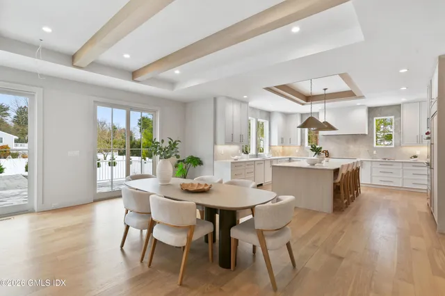 a kitchen with a dining table chairs sink and white cabinets