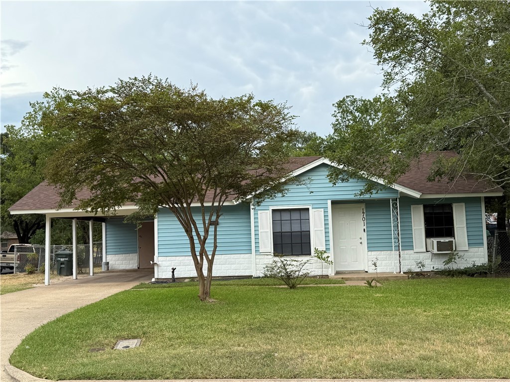 Single story home featuring a front lawn, concrete driveway, an attached carport, and roof with shingles