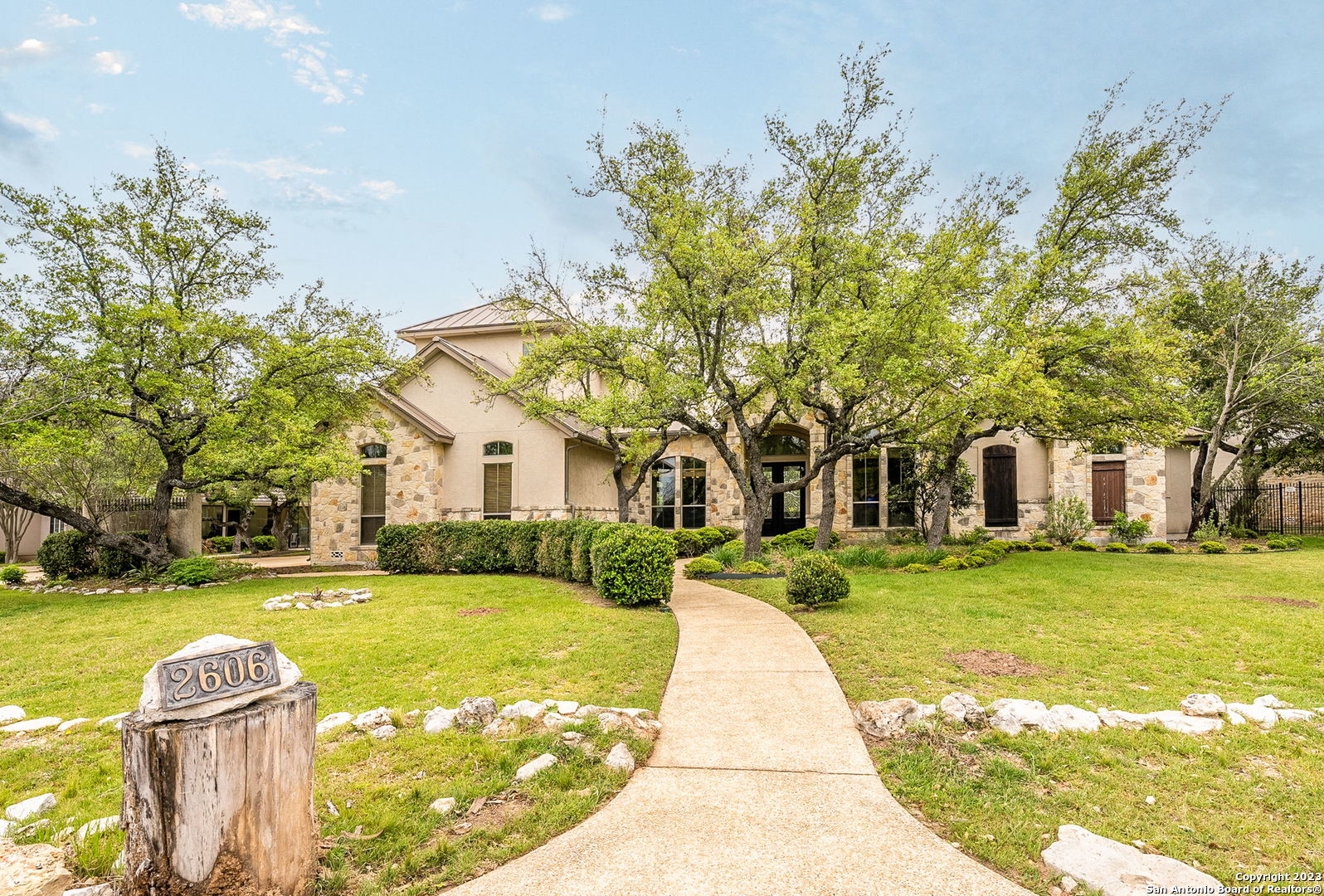 a front view of a house with a garden and trees