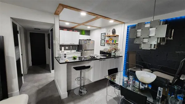 a kitchen with a refrigerator and chairs