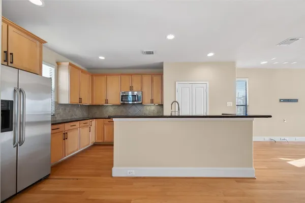 a large kitchen with stainless steel appliances a refrigerator a stove a sink and a microwave