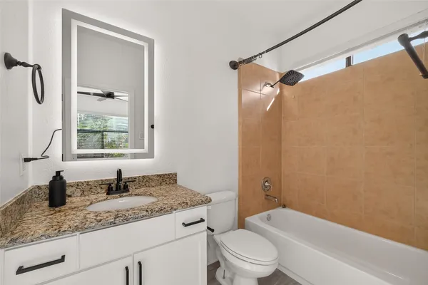 a bathroom with a granite countertop sink toilet and shower