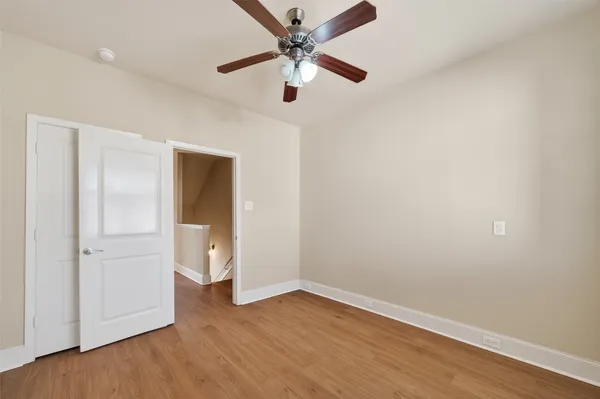 an empty room with wooden floor and ceiling fan