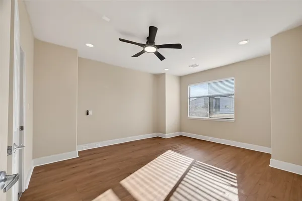 a view of an empty room with a window and wooden floor