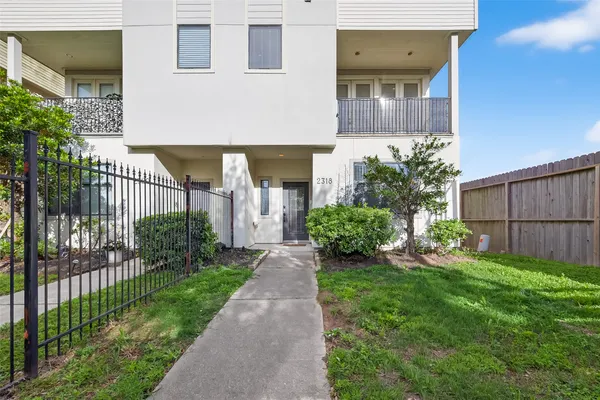a view of a house with a small yard and wooden fence