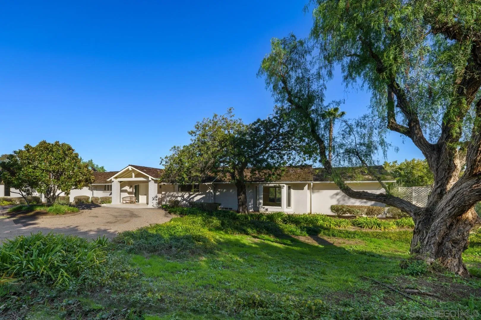 6531 Lago Lindo Rancho Santa Fe, CA 92067 - Photo 38 of 53 a view of a white house next to a yard with plants and trees