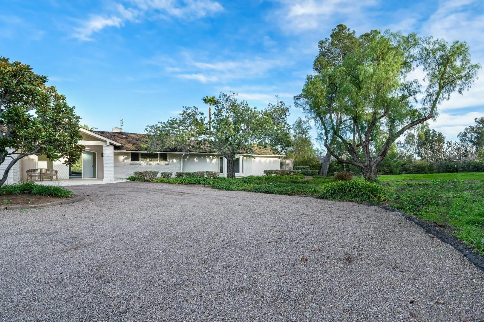 6531 Lago Lindo Rancho Santa Fe, CA 92067 - Photo 47 of 53 a view of a brick house next to a yard with big trees