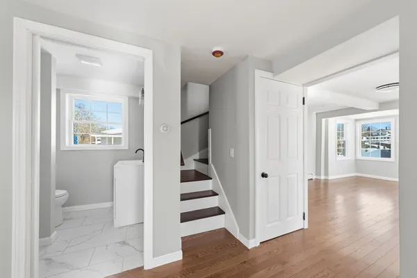 a view of a hallway with wooden floor and a living room