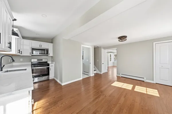 a view of a kitchen with wooden floor and stainless steel appliances