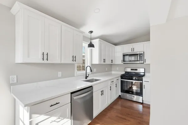 a kitchen with stainless steel appliances a sink stove and white cabinets