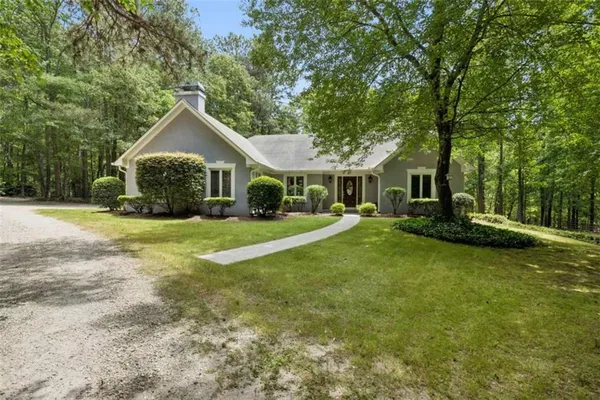 a view of a house with a big yard and large trees