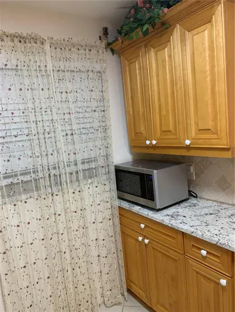 a kitchen with a sink a microwave cabinets and a window