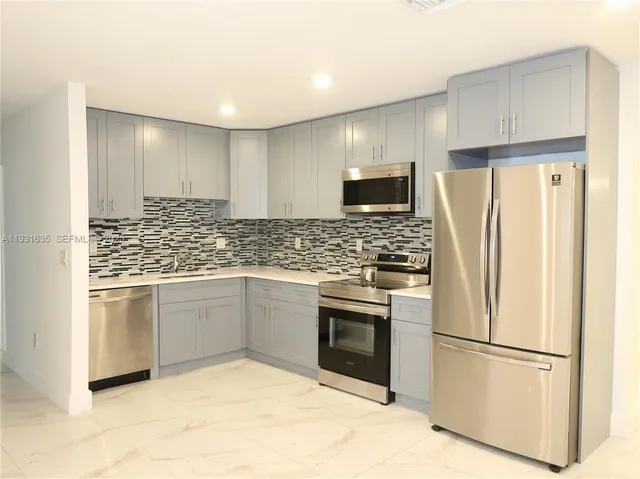 a kitchen with stainless steel appliances granite countertop a refrigerator sink and microwave