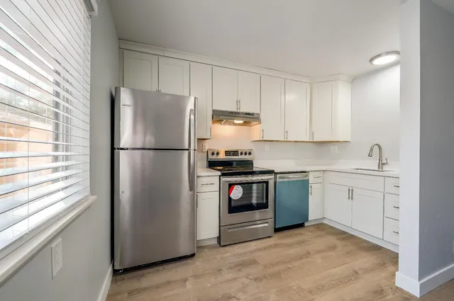 a kitchen with white cabinets and stainless steel appliances