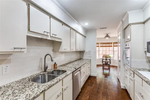 a kitchen with kitchen island granite countertop a sink a counter space appliances and cabinets