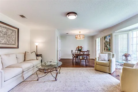 a living room with furniture and a dining table with bookshelf